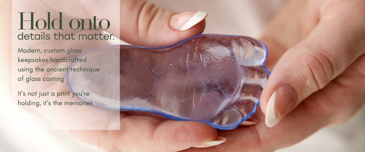 large banner of woman holding a detailed baby's blue footprint recreated in glass, with the words "Hold onto details that matter"